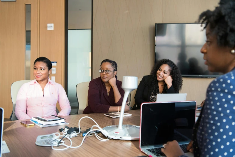 a group of people sitting around a table with laptops, by Everett Warner, unsplash, black female, in a meeting room, avatar image