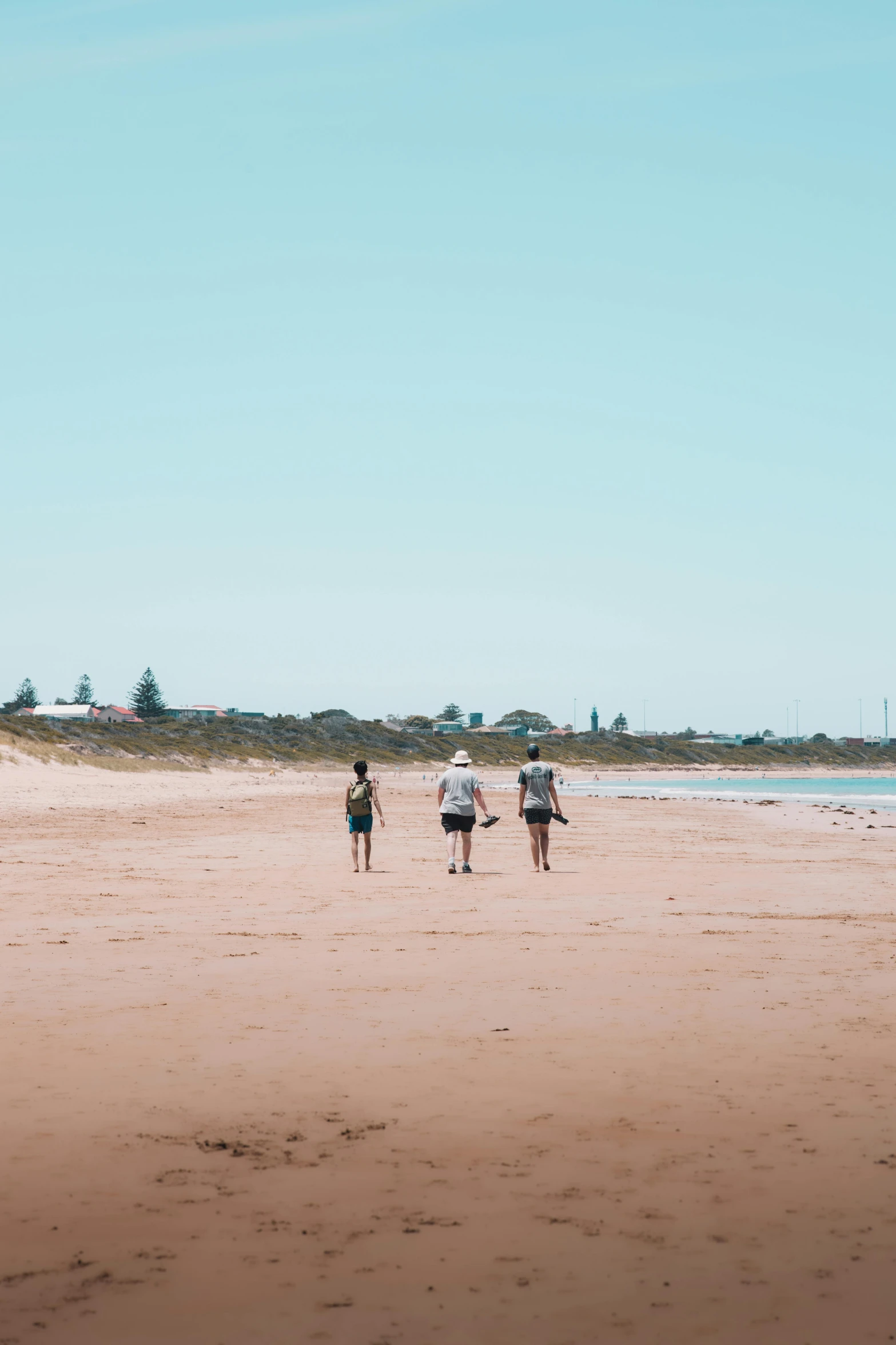 a group of people walking on top of a sandy beach, the beach