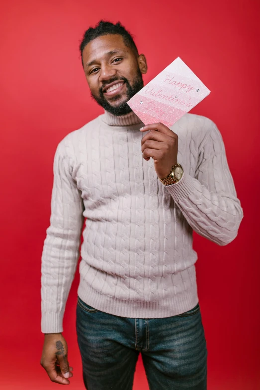 a man holding a piece of paper in one hand and a piece of paper in the other, an album cover, pexels contest winner, romanticism, red sweater and gray pants, mkbhd, joyful smirk, good at cards