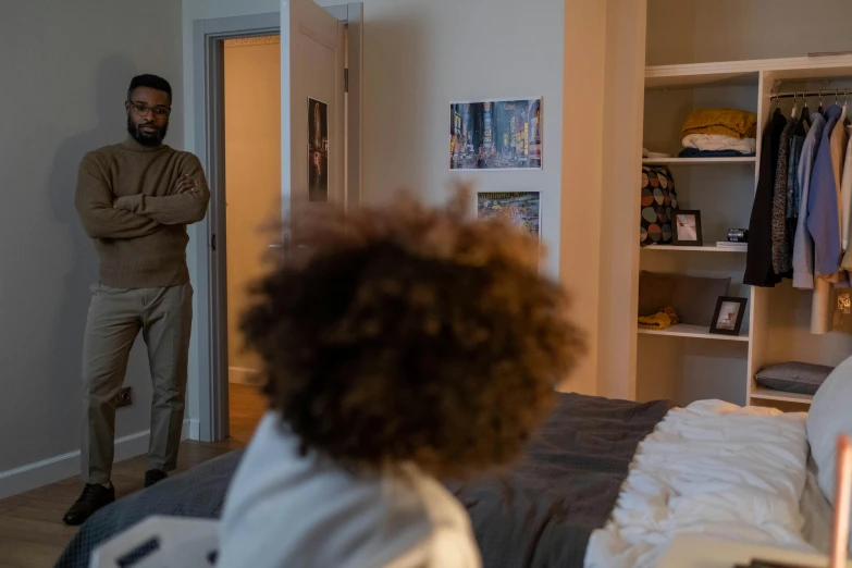 a man standing in a bedroom next to a bed, with a kid, jaylen brown, looking around a corner, realistic »