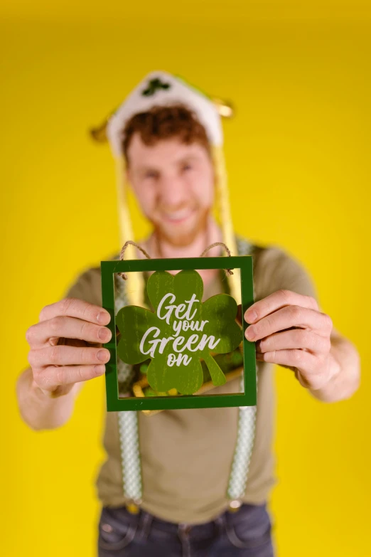 a man holding a green sign in front of his face, a polaroid photo, pexels contest winner, four leaf clover, wearing a straw hat and overalls, person made out of glass, eco-friendly theme