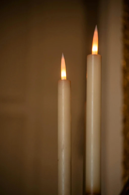 a couple of white candles sitting on top of a table, torches on wall, zoomed in, soft coloured gel lighting, spire