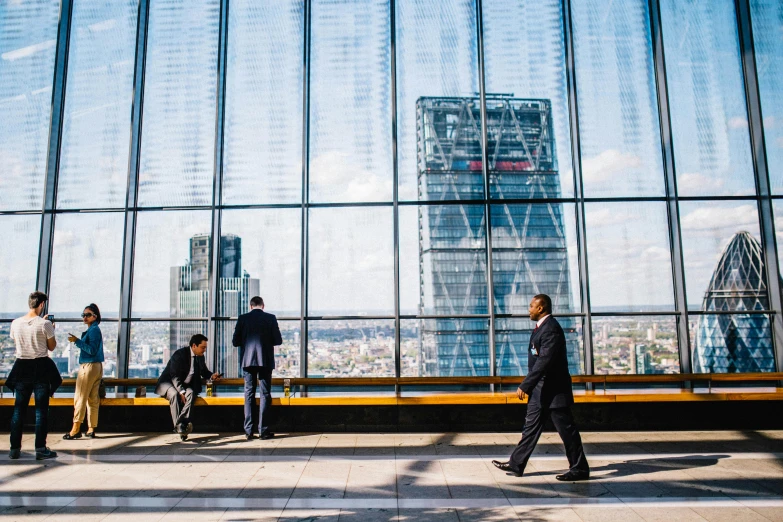 a group of people standing in front of a large window, by Tobias Stimmer, pexels contest winner, modernism, skyscrapers in the distance, man walking, norman foster, inside a grand