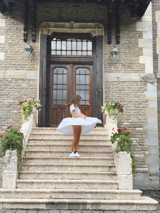 a woman sitting on the steps of a building, located in a castle, wearing white skirt, traveling in france, wearing crop top and miniskirt