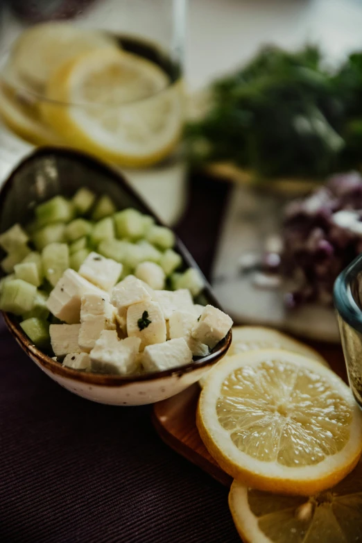 a close up of a plate of food on a table, cubes on table, lemons, light greens and whites, cheese