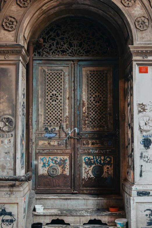 a door in an old building with graffiti on it, by Riad Beyrouti, pexels contest winner, baroque, rusted panels, dressed in ornate, 1910s architecture, multiple stories