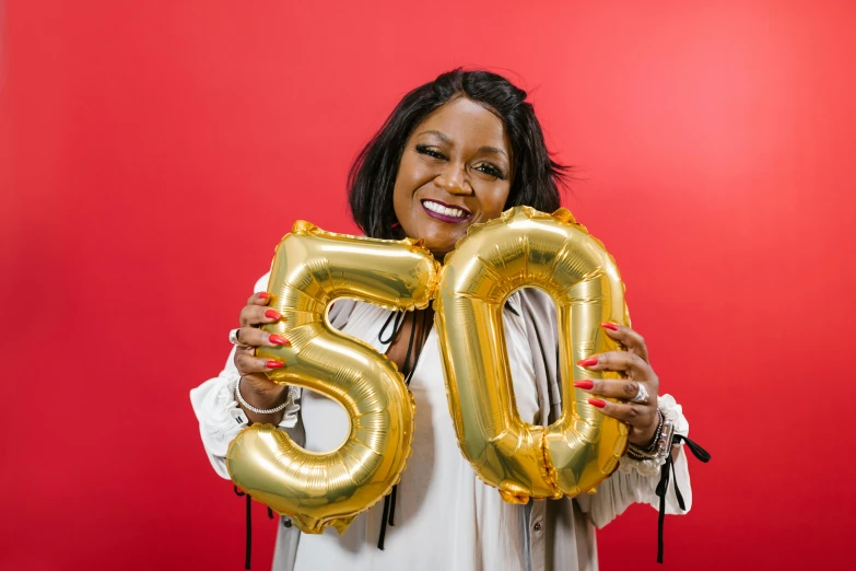 a woman holding up a golden number 50 balloon, by Matt Cavotta, pexels contest winner, ( ( dark skin ) ), mid - 3 0 s aged, plus size, celebrating a birthday