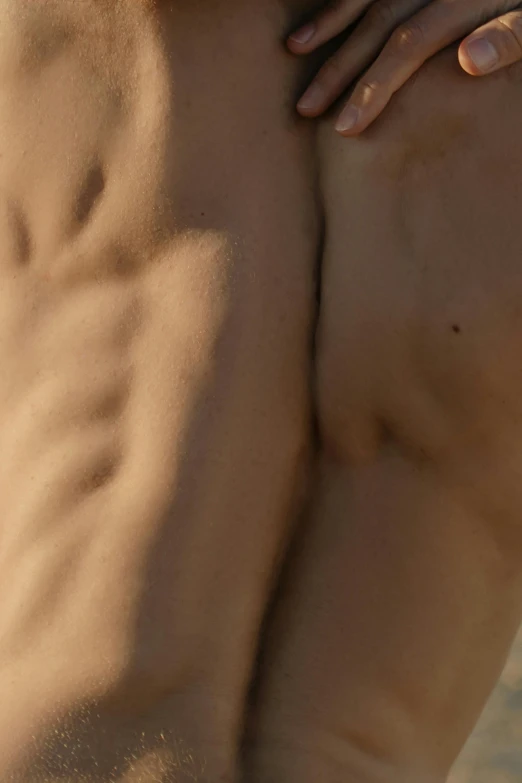 a man standing on top of a sandy beach, a tattoo, by Alexander Mann, reddit, photorealism, bottom body close up, vascularity, 30 year old man :: athletic, light tan