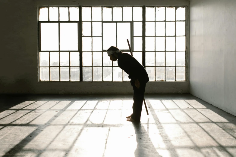 a person standing in a room in front of a window, inspired by Kanō Tanshin, unsplash, visual art, holding a crowbar, contemporary dance, kneeling at the shiny floor, ignant