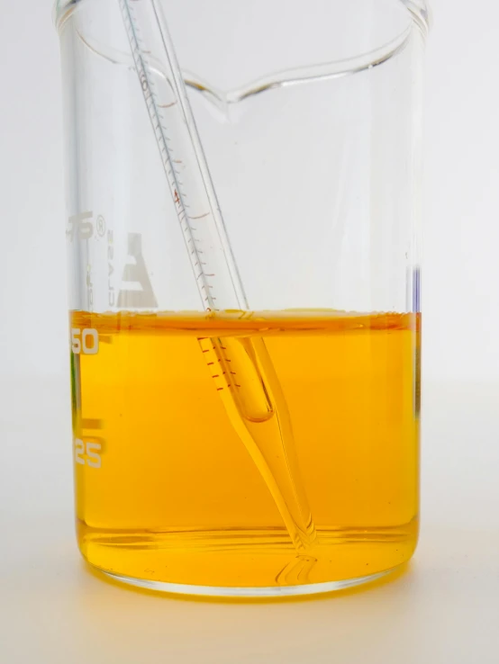 a close up of a beaker filled with liquid, golden ration, oils, light orange values, product shot