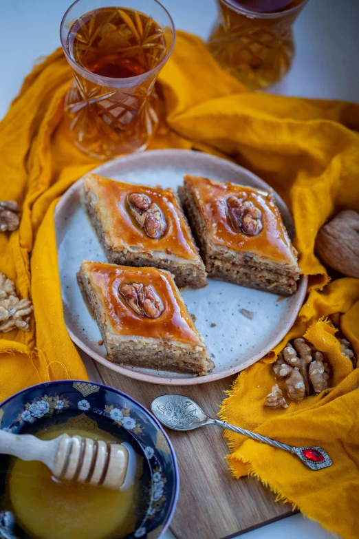 a plate topped with slices of cake next to a bowl of honey, by Julia Pishtar, hurufiyya, walnuts, thumbnail, orientalisme, silver
