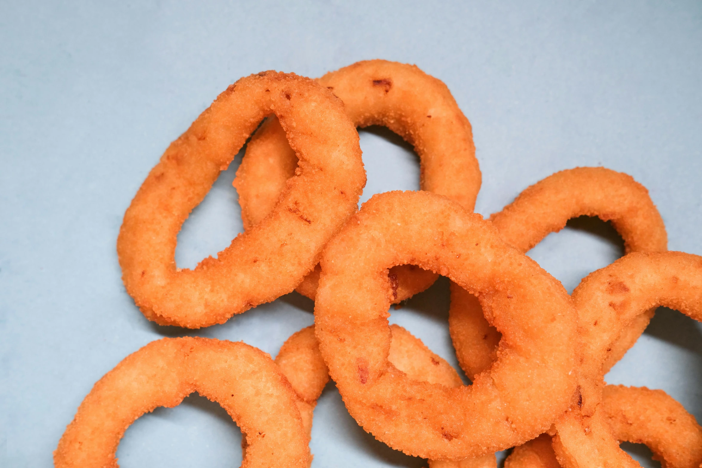 a pile of onion rings sitting on top of a table, on grey background, unclipped fingernails, thumbnail, oval eyes