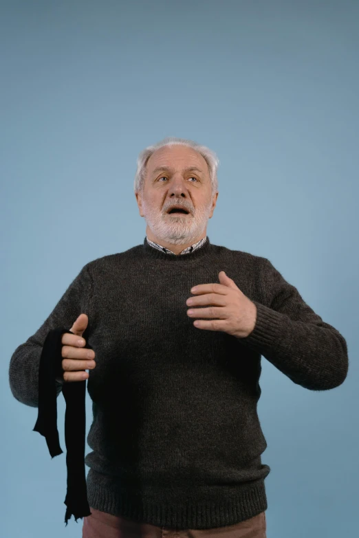 a man standing in front of a blue background, old gigachad with grey beard, gestures, webbing, wearing a scarf