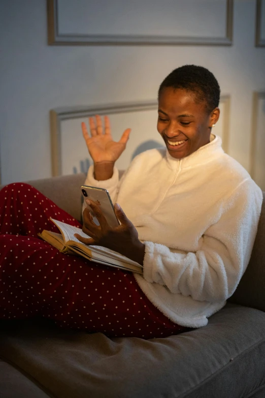 a woman sitting on a couch reading a book, happening, waving and smiling, black teenage boy, 2019 trending photo, wearing pajamas