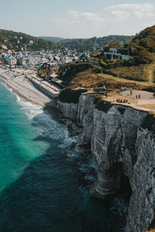 a group of people standing on top of a cliff next to the ocean, by Raphaël Collin, pexels contest winner, renaissance, quaint village, omaha beach, “ aerial view of a mountain, hd footage