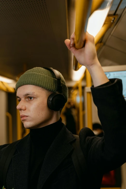 a man wearing headphones on a subway train, by Adam Marczyński, pexels, bauhaus, beanie, non-binary, dasha taran, indistinct man with his hand up