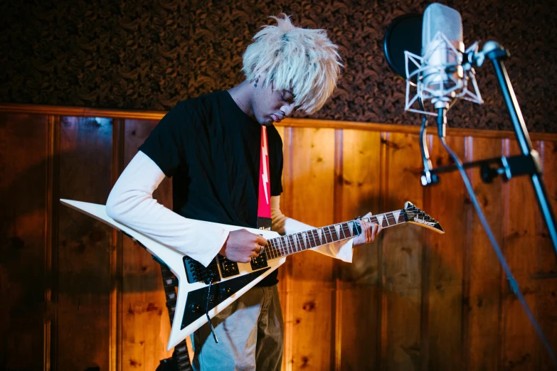 a man holding a guitar in front of a microphone, an album cover, inspired by Tadanori Yokoo, unsplash, realism, ayanami, platinum blond, practice, holding electric guitars