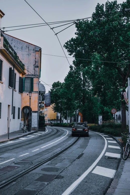 a car driving down a street next to tall buildings, pexels contest winner, renaissance, small town surrounding, humid evening, italy, low quality photo