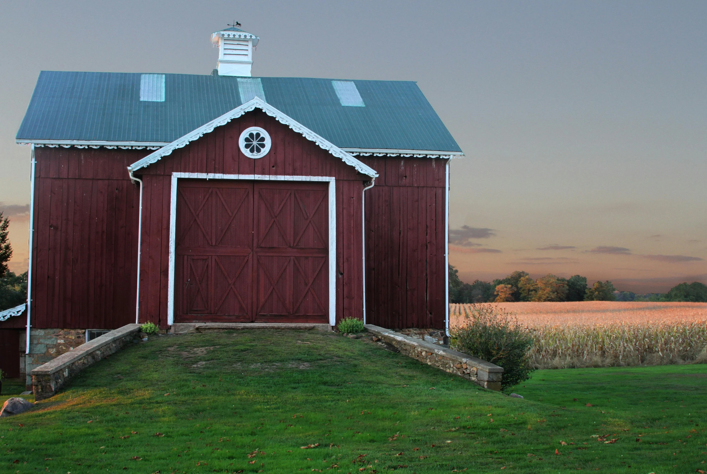 a red barn sitting on top of a lush green field, pexels contest winner, renaissance, evening at dusk, wine-red and grey trim, white plank siding, exterior shot