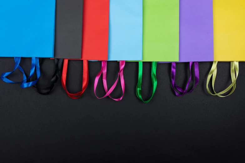 a row of colorful shopping bags on a black background, pexels contest winner, plasticien, black hair ribbons, matte black paper, thumbnail, no - text no - logo