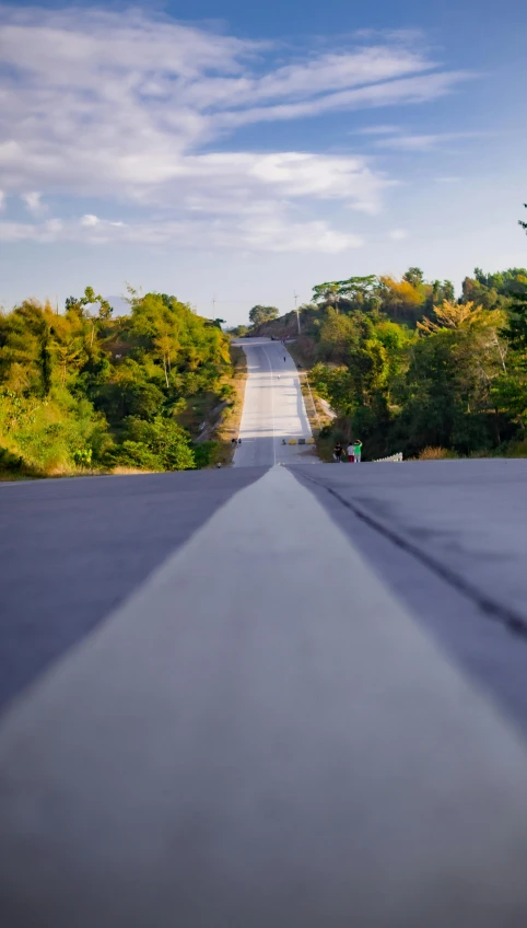 a man riding a skateboard down the middle of a road, an album cover, unsplash, mingei, hilly road, runway photo, japanese countryside, thumbnail