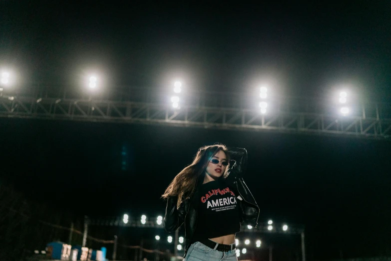 a woman standing on a skateboard in front of a stadium, pexels contest winner, antipodeans, rapping on stage at festival, :: madison beer, alexandria ocasio-cortez, people at night