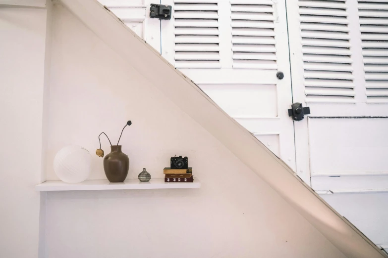 a vase sitting on top of a shelf next to a window, unsplash, light and space, stairs, trinkets, white background : 3, shutters