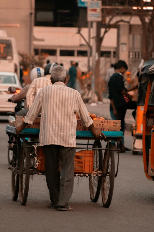 a man pushing a cart down a busy street, a picture, trending on unsplash, india, an oldman, square, orange