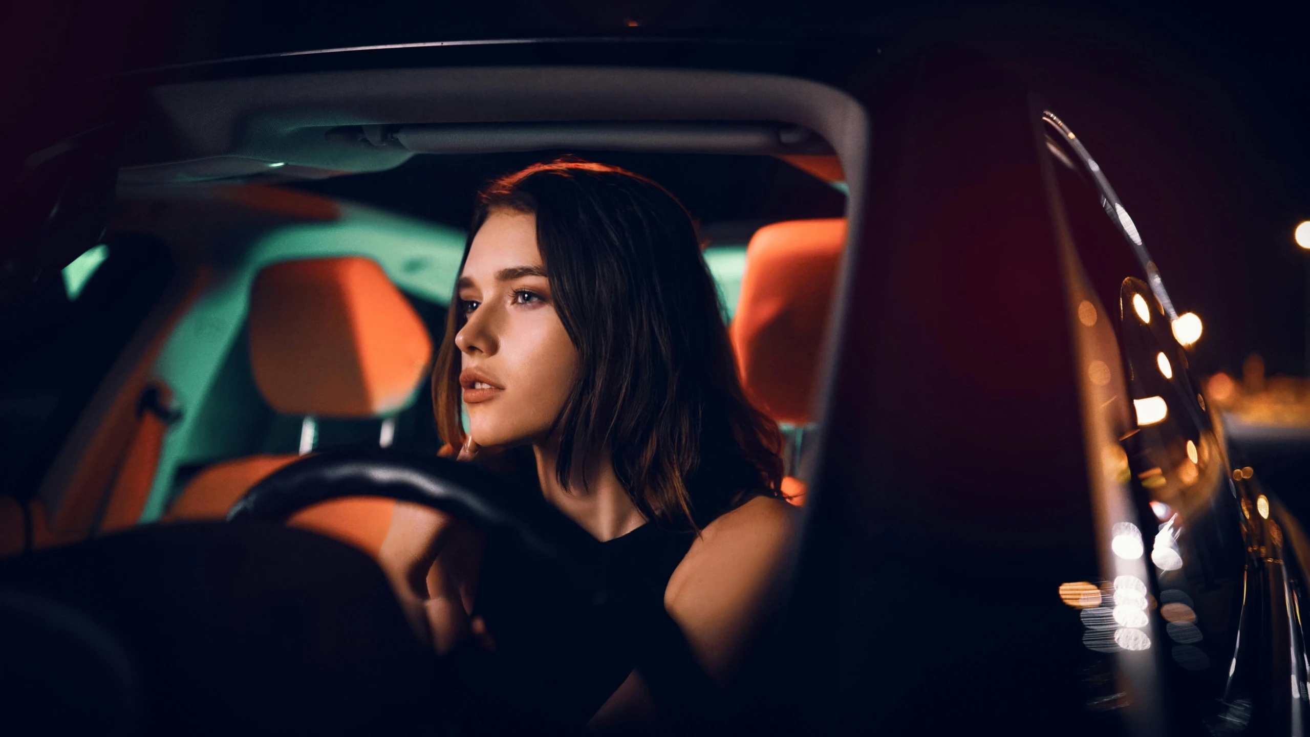a woman sitting in the driver's seat of a car, inspired by Elsa Bleda, unsplash contest winner, photorealism, subtle neon underlighting, girl with brown hair, dua lipa, handsome girl
