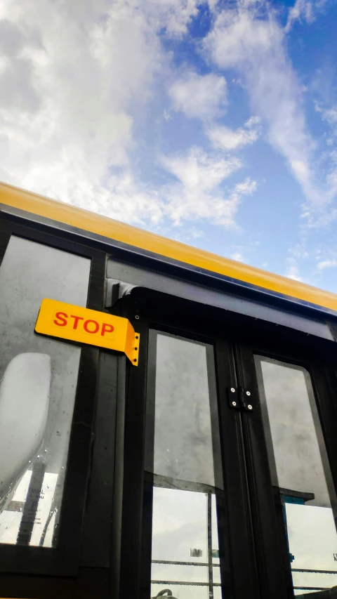 a stop sign on the side of a bus, by Dave Allsop, award winning shopfront design, yellow cap, schools, press shot