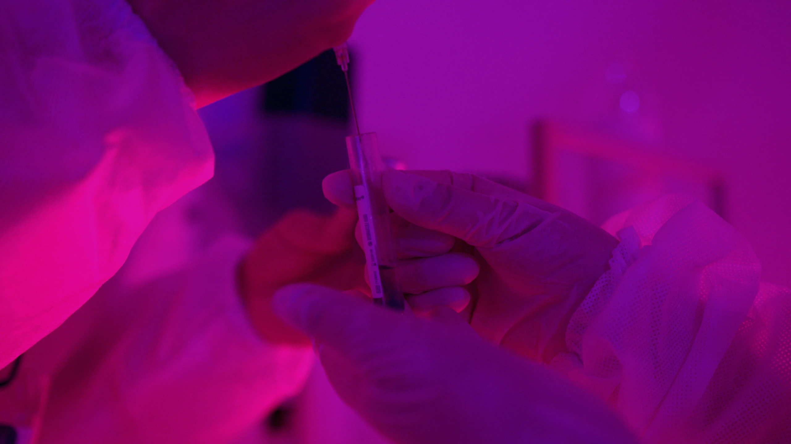 a close up of a person holding a cell phone, by Adam Marczyński, pexels contest winner, process art, holding syringe, brightly lit purple room, clone laboratory, pink