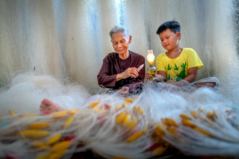 a couple of kids sitting on top of a bed, pexels contest winner, process art, vietnamese woman, netting, older woman, giant claws loom