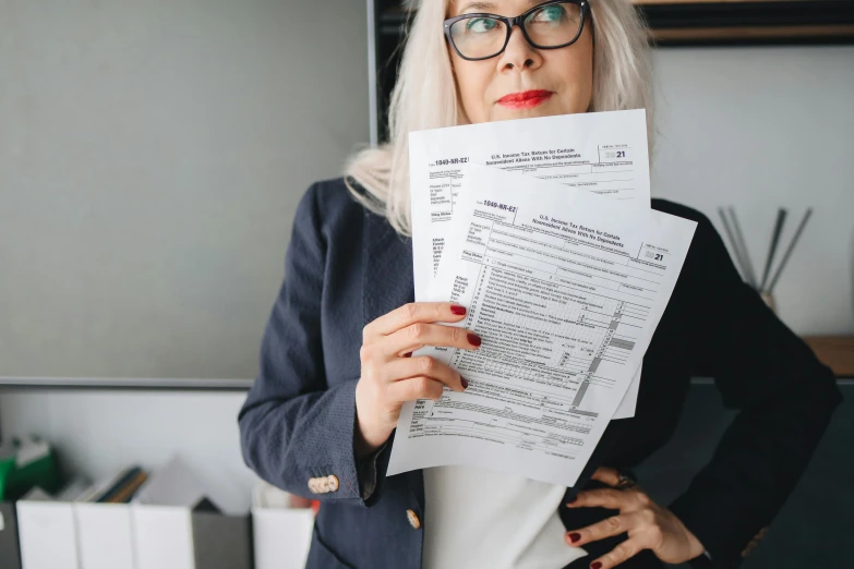 a woman with glasses holding papers in front of her face, by Adam Rex, pexels contest winner, character sheets on table, 15081959 21121991 01012000 4k, a person standing in front of a, white haired lady