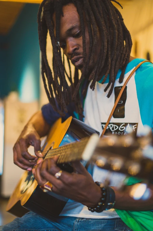 a man with dreadlocks playing a guitar, andrew tate, riyahd cassiem, local close up, multiple stories