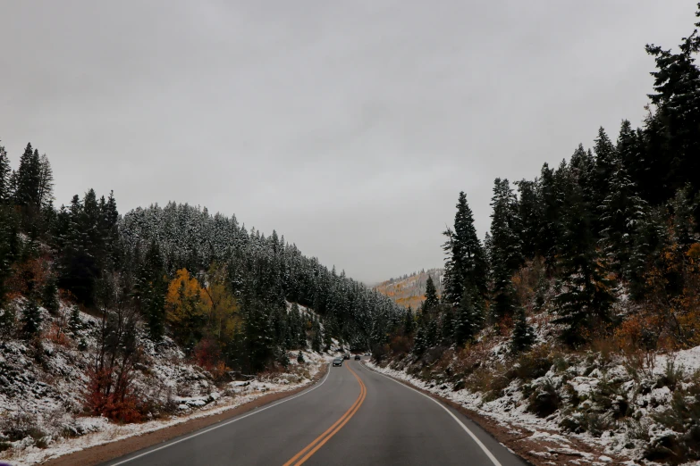 a car driving down a snow covered road, a picture, unsplash, renaissance, autumn mountains, overcast gray skies, long distance photo, canyon