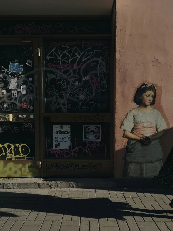 a man riding a bike down a sidewalk next to a building, a painting, pexels contest winner, graffiti, little girl, helsinki, vintage muted colors, sculpture of a woman