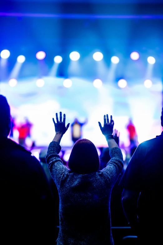 a group of people standing in front of a stage, by Dan Content, pexels, happening, pray, vibrant backlit, holding close, graphic”