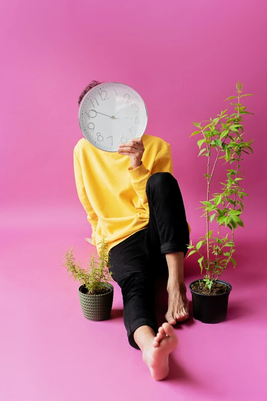 a person sitting on the ground with a frisbee over their head, an album cover, inspired by jeonseok lee, trending on pexels, houseplant, big clock, non binary model, profile image