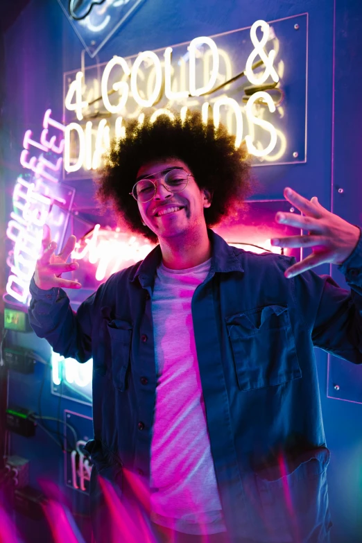 a man standing in front of a neon sign, an album cover, pexels, curly afro, dj at a party, high school, with a cool pose