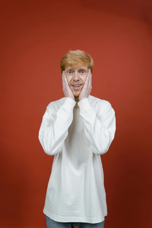 a man in a white shirt holding his hands to his face, an album cover, by Austin English, trending on pexels, renaissance, hr ginger, surprised, red face, 15081959 21121991 01012000 4k