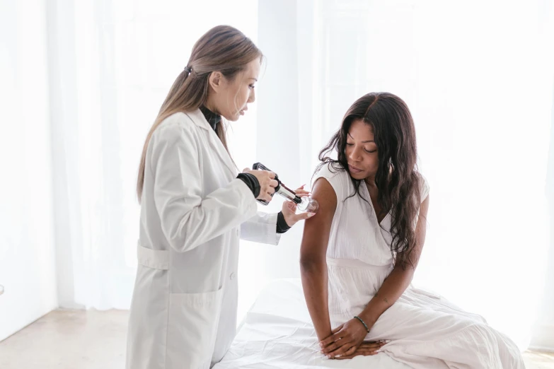 a doctor examining a woman's chest with a stethoscope, a photo, by Gavin Hamilton, pexels contest winner, renaissance, with brown skin, syringe, on a white table, an asian woman