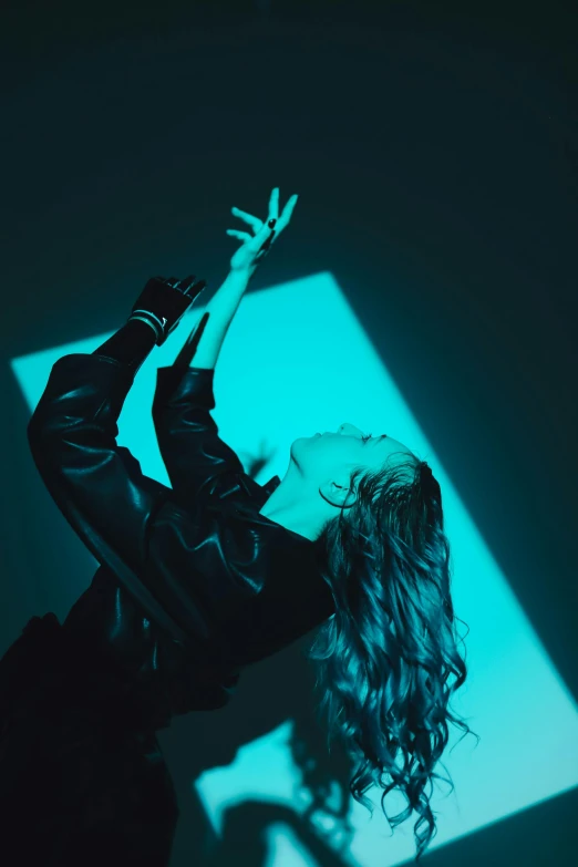 a woman standing in front of a blue light, an album cover, inspired by Elsa Bleda, trending on pexels, happening, dancing gracefully, wavy hair spread out, woman in black robes, hands up