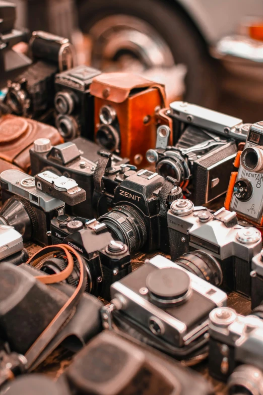 a pile of old cameras sitting on top of a table, inspect in inventory image, zoomed in shots, brown, red camera