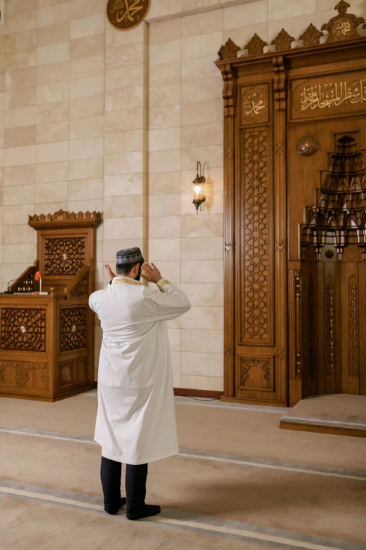 a man in a white coat talking on a cell phone, a picture, inspired by Kamāl ud-Dīn Behzād, hurufiyya, standing in front of the altar, white marble interior photograph, facing away from camera, jordan