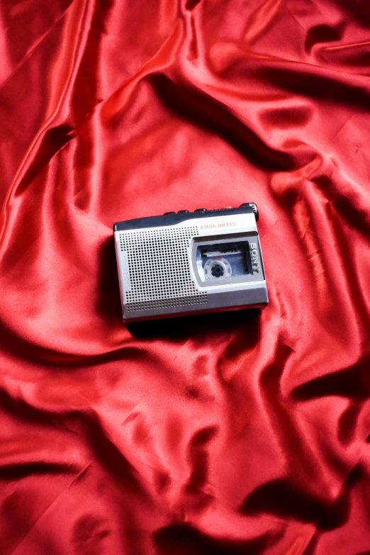 a radio sitting on top of a red cloth, inspired by Nan Goldin, trending on pexels, yashica t 4, silk, grey, ilustration