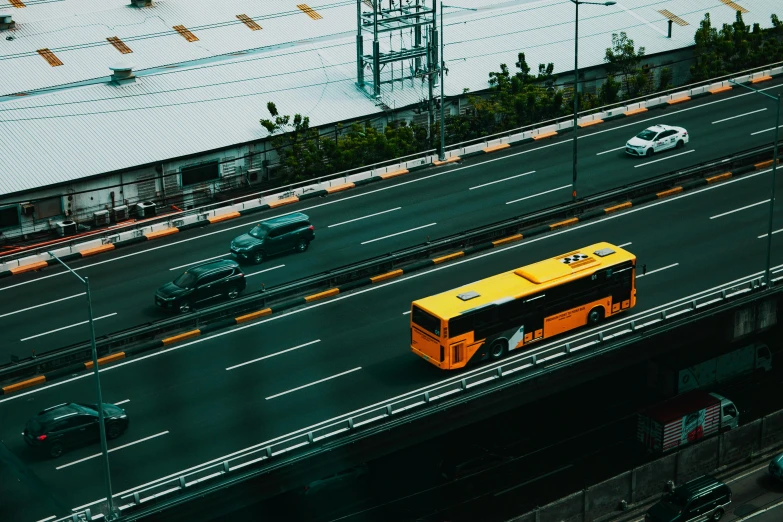 a yellow bus driving down a highway next to tall buildings, pexels contest winner, overpass, 🚿🗝📝, top-down shot, thumbnail