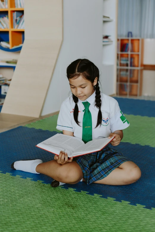 a girl sitting on the floor reading a book, danube school, nivanh chanthara, private school, high-quality photo, from reading to playing games