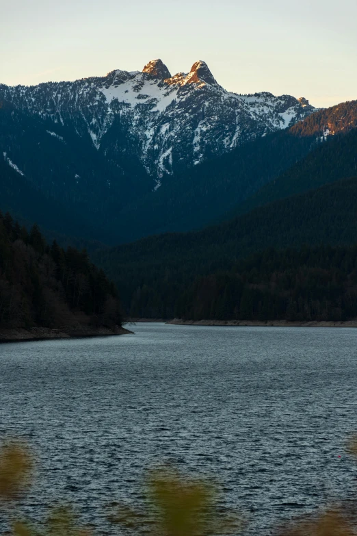 a body of water with mountains in the background, ominous! landscape of north bend, sun down, & a river, epic mountains