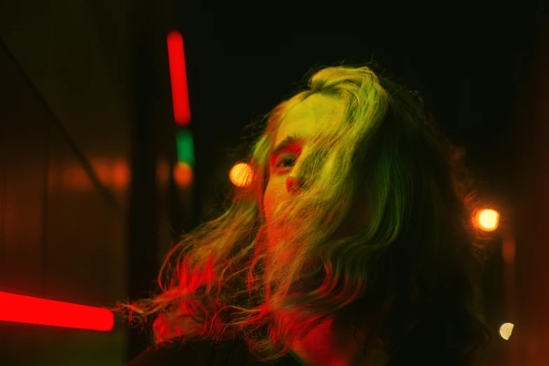 a woman with long blonde hair standing in a dark room, inspired by Elsa Bleda, pexels contest winner, synchromism, shades green and red, concert photo, a photo of a disheveled man, yellow lights