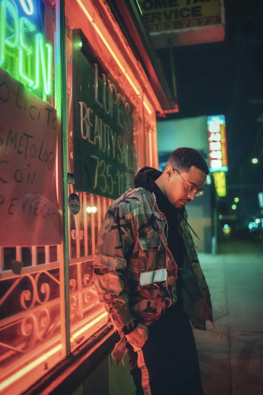 a man standing in front of a neon sign, an album cover, inspired by Liam Wong, pexels contest winner, realism, man with glasses, profile posing, neighborhood, xxxtentacion